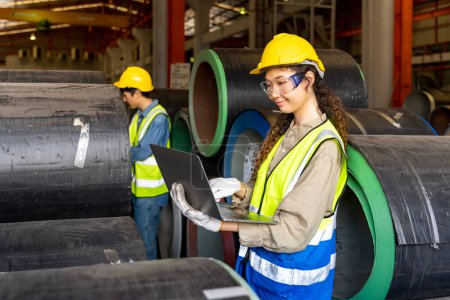 Asiatische Ingenieure inspizieren das Innere der Stahlblechfabrik, während sie auf den Laptop schauen, um die Verbesserung der Kapazität und Produktivität zu überwachen