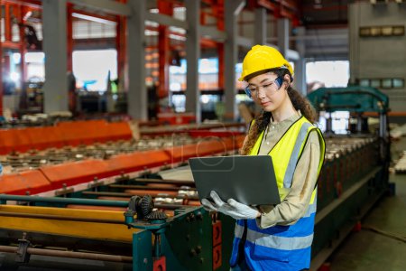 Téléchargez les photos : Travailleur ingénieur asiatique inspectant à l'intérieur de l'usine de fabrication d'acier tout en regardant l'ordinateur portable pour surveiller l'amélioration de la capacité et de la productivité - en image libre de droit