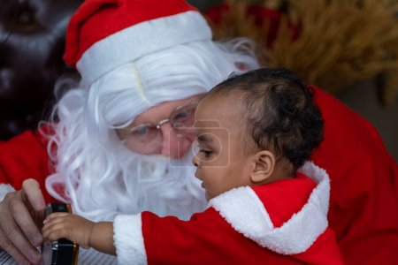 Téléchargez les photos : African American baby ouvre le cadeau de Noël avec le Père Noël la nuit pour la célébration de la saison concept - en image libre de droit