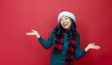 Téléchargez les photos : Jolie femme asiatique souriante en pull de Noël chaud et chapeau de Père Noël a excitation sur fond rouge pour le concept de célébration de la saison - en image libre de droit