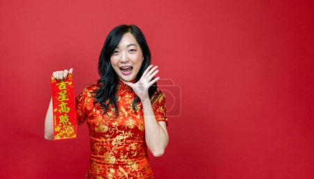 Photo for Asian woman holding red fortune blessing Chinese word which means "to be blessed by a lucky star" isolated on red background for Chinese New Year celebration - Royalty Free Image