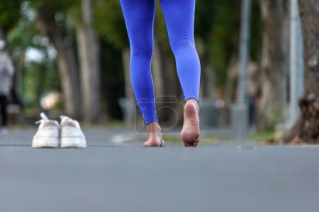 Corredor de la mujer está corriendo descalzo sin zapatos para evitar juanetes, achilles y otras lesiones en el pie como resultado de la caja estrecha del dedo del pie de los zapatos deportivos convencionales para construir una mejor fuerza muscular