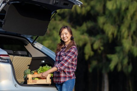 Téléchargez les photos : Asian farmer is delivering freshly harvest of organics vegetable box into the customer trunk car for supporting local business - en image libre de droit