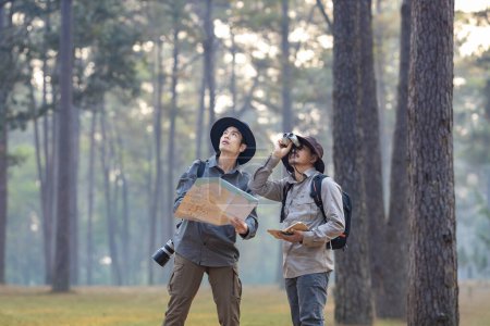 Foto de Equipo del naturalista asiático mirando el mapa mientras explora en el bosque de pinos para estudiar y descubrir la rara diversidad biológica y ecologista en el estudio de campo - Imagen libre de derechos