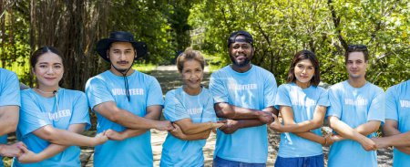 Téléchargez les photos : Une équipe de jeunes travailleurs bénévoles de la diversité profitent du travail social de bienfaisance en plein air dans un projet de plantation de mangroves portant un t-shirt bleu tout en unissant leurs efforts pour rassembler l'unité - en image libre de droit
