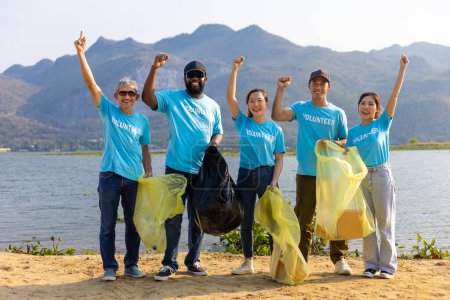 Foto de Equipo de jóvenes y grupos de voluntarios de diversidad disfrutan de trabajo social caritativo al aire libre en la limpieza de la basura y el proyecto de separación de residuos en la playa del río - Imagen libre de derechos