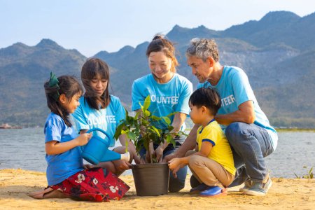 Téléchargez les photos : Équipe d'un groupe de bénévoles enseignant aux enfants à planter des arbres dans le cadre d'un travail social caritatif sur la forêt reconstituant le travail des ONG pour lutter contre le changement climatique et le réchauffement climatique dans le concept d'habitat côtier - en image libre de droit