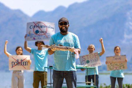 Foto de Equipo de voluntarios ecologistas están demostrando manifestación en el océano por el cambio climático y salvando la naturaleza con un cartel de protesta contra la contaminación y la contaminación del mar para la vida silvestre y la biodiversidad - Imagen libre de derechos