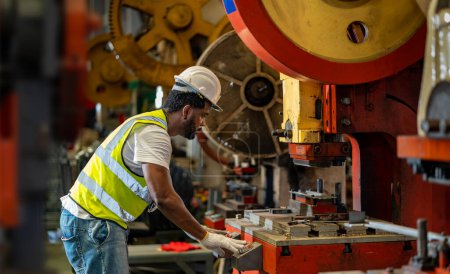 Téléchargez les photos : Le travailleur industriel afro-américain utilise une presse hydraulique pour fabriquer des pièces métalliques et en acier tout en travaillant à l'intérieur de l'usine de toiture galvanisée en tôle pour l'industrie de la sécurité - en image libre de droit