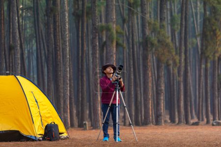 Foto de Naturalista asiático mirando a nuevas especies de aves descubriendo mientras explora en el bosque de pinos en el camping para estudiar y localizar la rara diversidad biológica y ecologista en el estudio de campo - Imagen libre de derechos