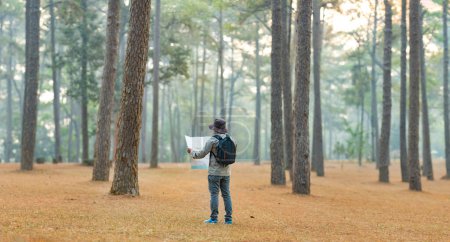 Photo for Asian naturalist looking at the map for direction while exploring wildlife in the pine forest for surveying and discovering the rare biological diversity and ecologist on the field study - Royalty Free Image