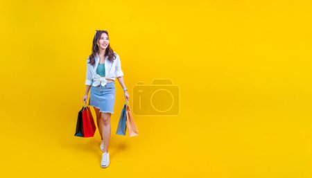 Foto de Mujer asiática bonita en moda de verano de moda está sonriendo y sosteniendo bolsa de compras en la felicidad para la venta de descuento aislado en el fondo amarillo para la publicidad y promoción concepto de evento - Imagen libre de derechos