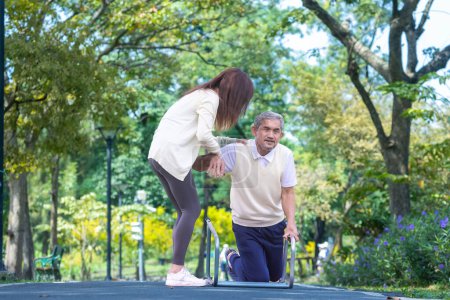 Photo for Asian senior man is accidentally fall over in the park due to the slippery road while his niece is lifting him up in injury for elder care and knee surgery recovery concept - Royalty Free Image