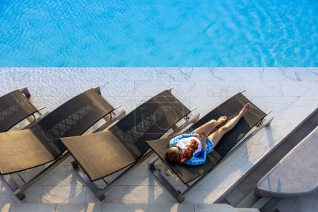 Téléchargez les photos : Vue de dessus de la femme couchée sur le lit de la piscine portant des lunettes de soleil dans un complexe de luxe pendant les vacances d'été pour les voyages de destination tropicale et les loisirs de plein air - en image libre de droit