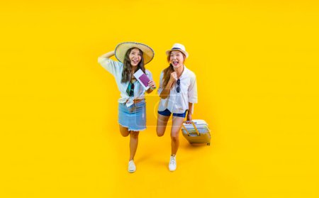 Photo for Two Pretty asian women passenger in trendy fashion is exciting to board while carrying her luggage bag in happiness for friendly trip and summer travel vacation isolated on yellow background - Royalty Free Image