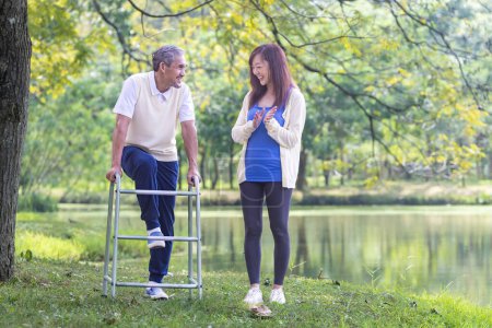 Photo for Asian senior man with walker and his daughter walking together in the park doing light exercise and physical therapy for muscle building in longevity and healthy lifestyle after retirement concept - Royalty Free Image
