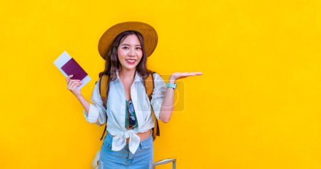 Foto de Pasajera asiática bonita sostiene pasaporte con tarjeta de embarque para viajes y vacaciones de verano aislada sobre fondo amarillo con espacio para copias. - Imagen libre de derechos