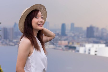 Photo for Asian woman tourist enjoying her rooftop panoramic view with cityscape background for vacation and travel concept - Royalty Free Image