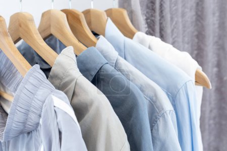 Téléchargez les photos : Rack de chemises en coton bleu et gris sur le placard ouvert au magasin de vente au détail d'occasion pour des produits textiles respectueux de l'environnement et la couleur de plage teinte naturelle biologique - en image libre de droit