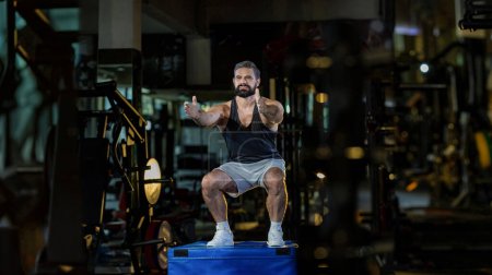 Photo for Caucasian man with strong and muscular firm shape is training on leg day by doing advance jump squat for thigh and calf muscle in the gym for healthy and strong lower body weight strength - Royalty Free Image