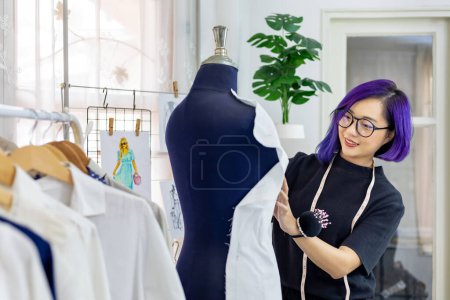 Photo for Fashionable freelance dressmaker is pinning her marking muslin for new dress by pinning to mannequin while working in the artistic workshop studio for fashion design and clothing business industry - Royalty Free Image