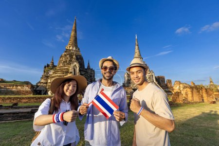 Foto de Grupo de turistas en su mochilero con bandera tailandesa están viajando al antiguo templo de Phra Si Sanphet, Ayutthaya, Tailandia para el turismo y el concepto de turismo - Imagen libre de derechos
