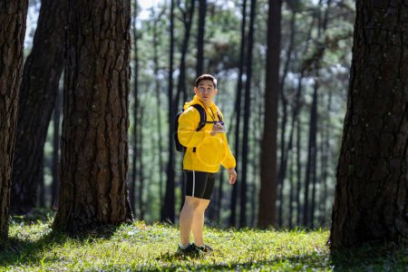Foto de El excursionista de la naturaleza sostiene binoculares mientras explora en el bosque de pinos para estudiar y descubrir la rara diversidad biológica y el ecólogo en el concepto de estudio de campo de senderismo. - Imagen libre de derechos