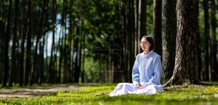 Téléchargez les photos : Femme pratiquant la méditation relaxante dans la forêt de pins pour atteindre le bonheur de la paix intérieure sagesse avec rayon de lumière du soleil pour un esprit et une âme sains pour un esprit et une âme sains - en image libre de droit