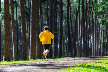 Photo for Back view of trail runner is running outdoor in the pine forest dirt road for exercise and workout activities training to race in ultra marathon achieving healthy lifestyle and fitness - Royalty Free Image