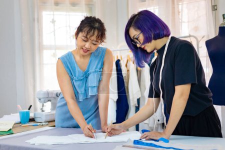 Photo for Team of fashionable freelance dressmakers making adjustment on muslin for new custom made dress while working in the artistic workshop studio for fashion design and clothing business industry - Royalty Free Image