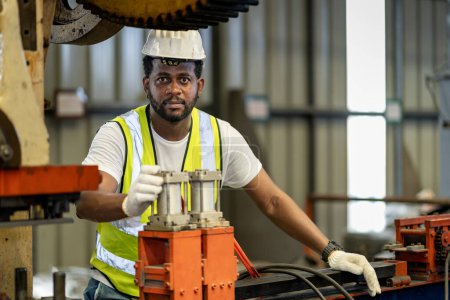 Téléchargez les photos : Le travailleur industriel afro-américain utilise une machine de presse hydraulique pour fabriquer des pièces métalliques et en acier tout en travaillant à l'intérieur d'une usine de toiture galvanisée en tôle pour l'industrie de la sécurité - en image libre de droit