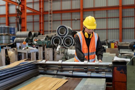 Téléchargez les photos : Travailleur industriel asiatique vérifie la valeur d'installation du rouleau de tôle formant la machine à l'intérieur de l'usine de toit pour la construction de l'industrie de la sécurité - en image libre de droit