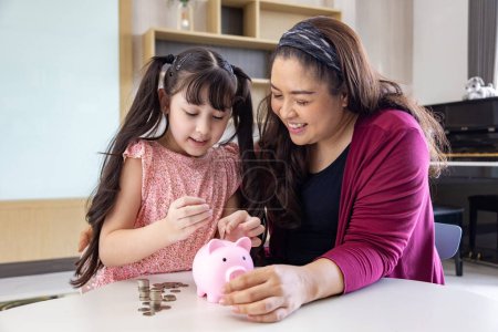 Téléchargez les photos : Mère asiatique enseigne à sa fille la leçon d'épargne pour l'investissement dans l'éducation et la planification future - en image libre de droit