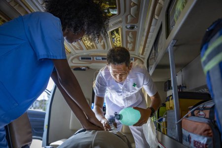 Téléchargez les photos : L'équipe d'ambulanciers aide le patient âgé qui cesse de respirer à la suite d'un accident de voiture en utilisant un respirateur pour une crise cardiaque et des accidents de la rue. - en image libre de droit