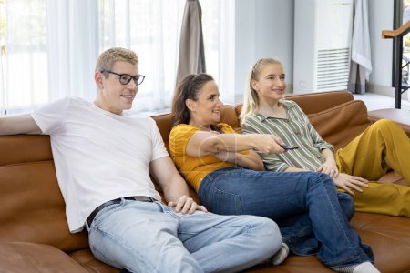 Téléchargez les photos : Un ami caucasien et sa famille passent du temps ensemble à regarder un film dans le salon à la maison pour le week-end et les activités de vacances dans le concept de loisirs et de bonheur - en image libre de droit