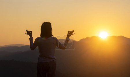 Téléchargez les photos : Panorama vue arrière de la femme pratique le yoga de méditation relaxant au sommet de la montagne avec le soleil levant en été pour atteindre le bonheur de la paix intérieure sagesse pour un esprit et une âme sains - en image libre de droit