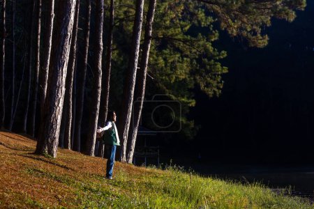 Foto de Naturalista está de excursión a destino mientras recibe la energía curativa en el bosque de pinos junto al lago para estudiar y descubrir la rara diversidad biológica y ecologista en el estudio de campo durante la mañana - Imagen libre de derechos