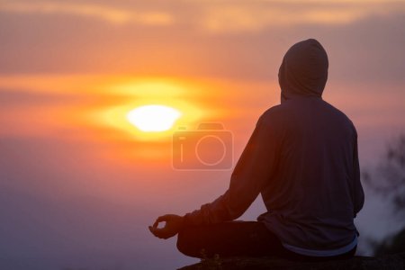 Téléchargez les photos : Vue arrière de l'homme pratique relaxante méditation yoga mudra au sommet de la montagne avec lever de soleil pendant l'hiver pour atteindre le bonheur de la paix intérieure sagesse pour un esprit sain et l'âme - en image libre de droit