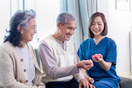 Senior couple got medical service visit from caregiver nurse while using round squishy ball for muscle strength in pension retirement center for rehabilitation and longevity post recovery process