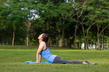 Photo for Asian woman relaxingly practicing cobra pose meditation yoga and stretching inside the forest to attain happiness from inner peace wisdom for healthy mind and soul - Royalty Free Image
