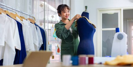 Photo for Fashionable freelance dressmaker is pinning her marking collar for new dress by pinning to mannequin while working in her artistic workshop studio for fashion design and clothing business industry - Royalty Free Image