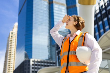 Foto de La ingeniera caucásica está mirando por encima del edificio de gran altura mientras inspecciona el proyecto de construcción para la arquitectura moderna y el desarrollo inmobiliario - Imagen libre de derechos