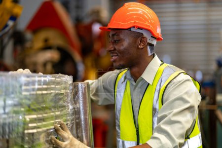 Foto de Trabajador industrial afroamericano está inspeccionando dentro de la fábrica de techos galvanizados de chapa metálica para el concepto de industria de seguridad - Imagen libre de derechos