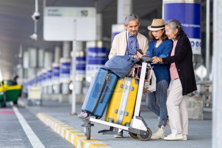 Group of Asian family tourist passenger with senior is using mobile application to call pick up taxi at airport terminal for transportation during the vacation travel and long weekend holiday