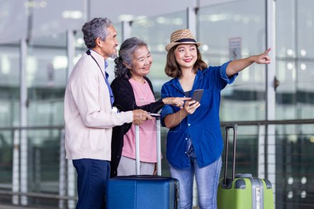 Foto de Grupo de pasajeros turísticos familiares asiáticos con adulto mayor está utilizando la aplicación móvil para llamar recoger un taxi en la terminal del aeropuerto para el transporte durante sus viajes de vacaciones y largas vacaciones de fin de semana - Imagen libre de derechos