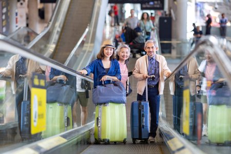 Foto de Grupo de pasajeros turísticos familiares asiáticos con padres mayores que utilizan escaleras mecánicas en la terminal del aeropuerto para viajar en avión y el concepto de vacaciones de vacaciones - Imagen libre de derechos
