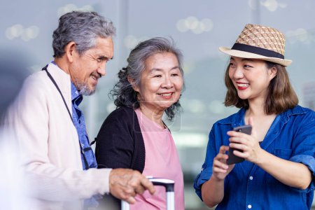 Foto de Grupo de pasajeros turísticos familiares asiáticos con adulto mayor está utilizando la aplicación móvil para llamar recoger un taxi en la terminal del aeropuerto para el transporte durante el viaje de vacaciones y largas vacaciones de fin de semana - Imagen libre de derechos