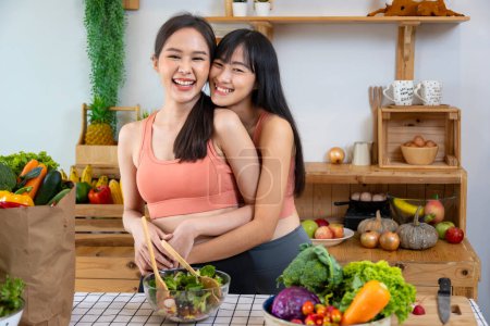 Photo for Asian couple of same sex marriage hugging each other while cooking healthy salad together at kitchen during pride month to promote equality and differences of homosexual and discrimination - Royalty Free Image