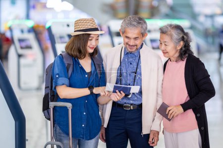 Foto de Grupo de pasajeros turísticos de la familia asiática con padres mayores está buscando en la tarjeta de embarque después de autocheck kiosco en la terminal del aeropuerto para el vuelo de viaje internacional y vacaciones - Imagen libre de derechos