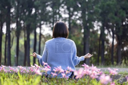 Téléchargez les photos : Femme asiatique fait la méditation mudra dans la forêt avec bulbe fleur de printemps en saison de floraison pour la paix intérieure, pleine conscience et zen concept de pratique - en image libre de droit